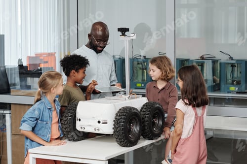 Preview: Group of clever intercultural pupils and their teacher of robotics using tablet