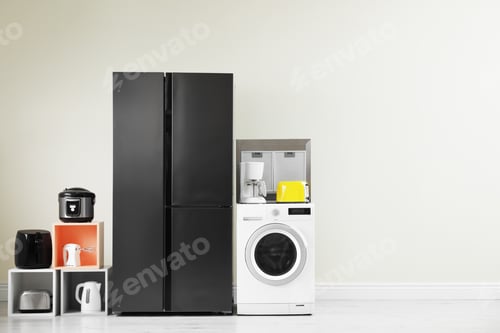 Preview: Modern refrigerator and other household appliances near beige wall indoors, space for text