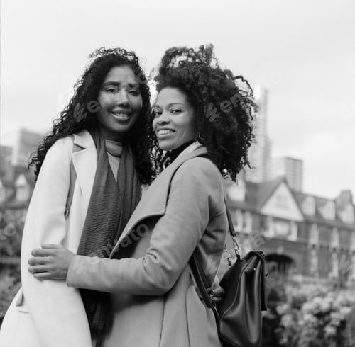Preview: Analog portrait of two female friends posing in the street with affection.