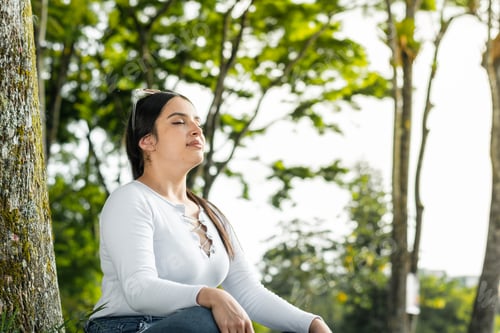 Preview: latina woman thinking and meditating in the middle of nature, raising her head to get some fresh air