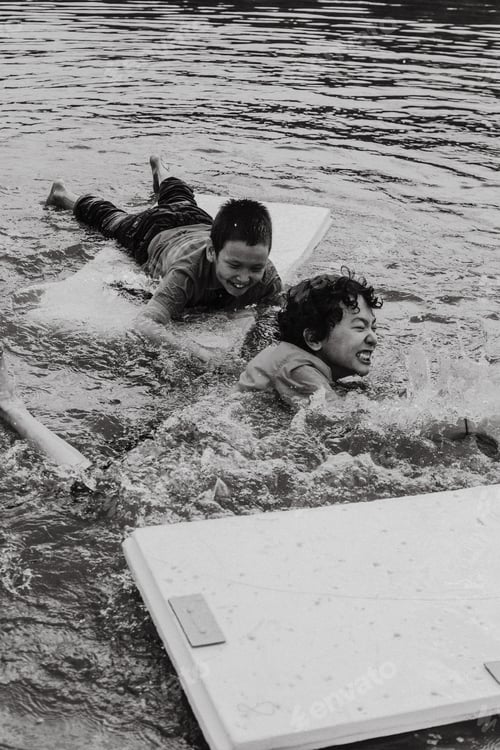 Preview: Happy kids lying on board over rough water