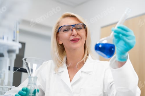 Preview: Blonde scientist observing liquid in flask in chemistry lab