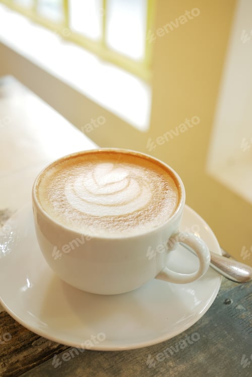Preview: a cup of late coffee with flower shape design on top at cafe