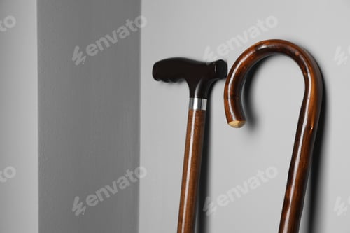 Preview: Two Elegant Wooden Walking Canes Against Gray Wall