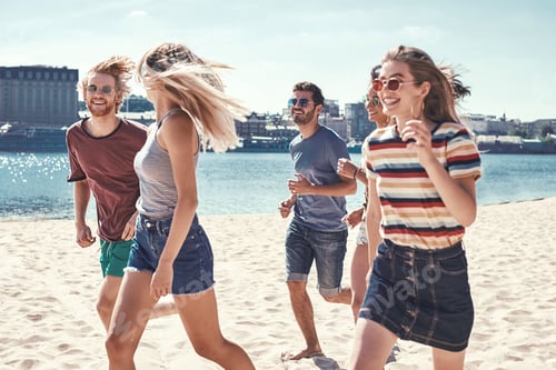 Preview: Friends on the beach. Happy young friends group have fun and celebrate while jumping and running on