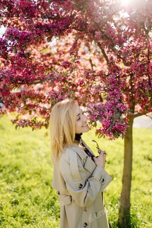Preview: Caucasian blonde woman wearind trench smile happily on sunny spring day outside walking in park