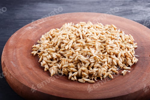 Preview: Heap of germinated oats on brown wooden board, close up.