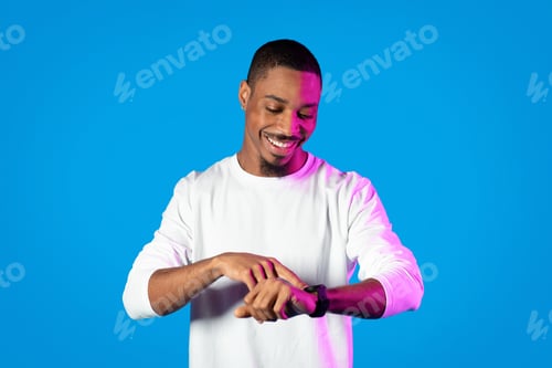Preview: Happy black man checking time on smartwatch on hand