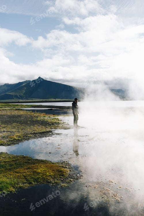 Preview: Man stand over geyser lake in iceland