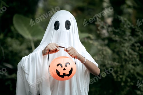 Preview: A young boy dressed as a ghost for Halloween wears a white sheet with black eye holes
