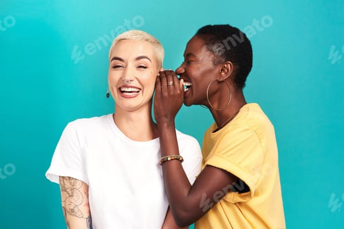 Preview: Studio shot of a young woman whispering in her friends ear against a turquoise background