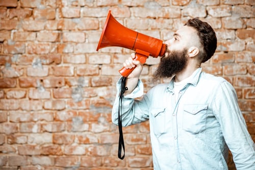 Preview: Man with loudspeaker on the brick background