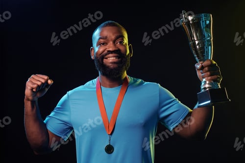 Preview: Black Sportsman Holding Cup and Celebrating Victory