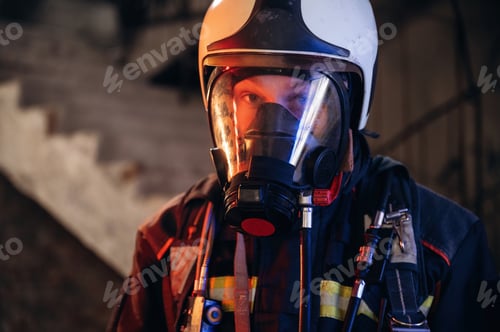 Preview: By the help of air mask. Firefighter in professional equipment is indoors in abandoned building