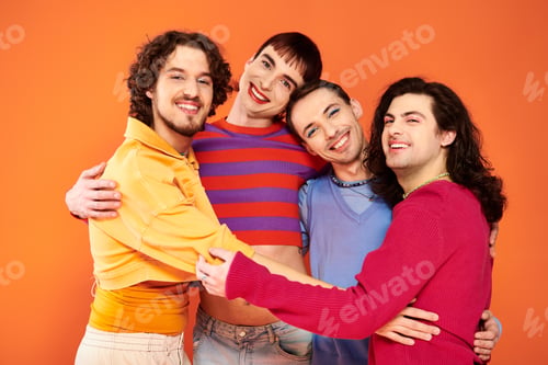 Preview: cheerful debonair gay men with makeup in vibrant attires posing actively together, pride month