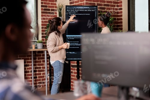 Preview: Team of coders talking about algorithms in front of big screen