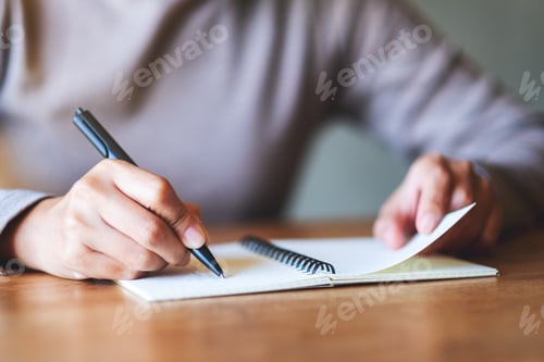 Preview: Closeup image of a woman writing on a blank notebook on the table