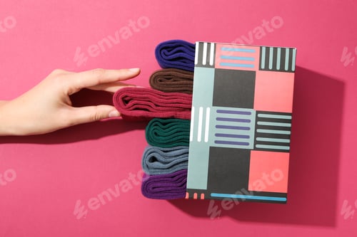 Preview: Box with socks and female hand on pink background