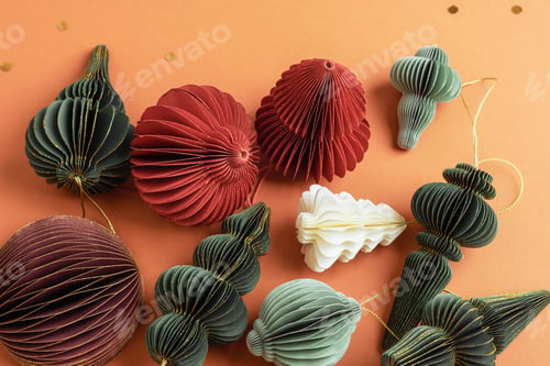Preview: Paper Christmas ornaments in red, green and white colors on orange background. Top view
