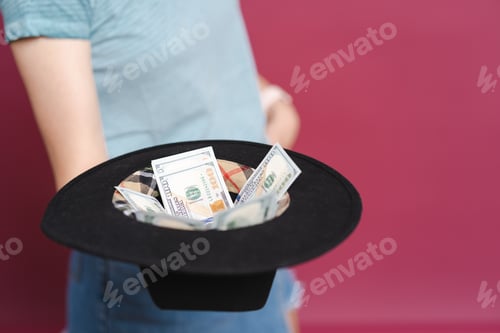 Preview: Portrait of joyful lucky woman in casual t shirt happy to hold lot a hat with money