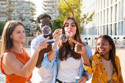 Preview: Multiracial group of happy friends having fun with soap bubbles in the city - Cheerful young friends