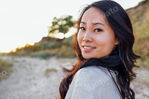 Preview: Young attractive Asian with long wavy hair outdoors. A charming Korean woman