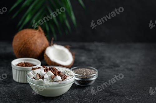 Preview: Coconut pudding with granola and chia on dark background. Healthy breakfast, copy space.