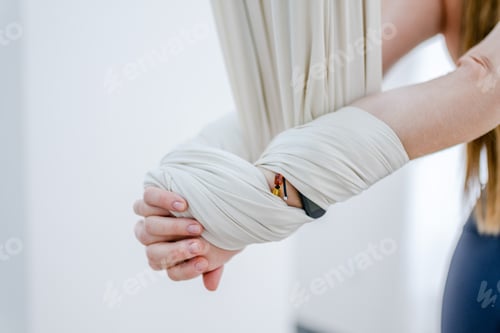 Preview: woman stands with her arms closed behind her back using white hammock for aerial fly yoga