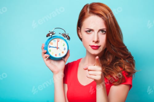 Preview: Redhead girl with alarm clock on blue background.