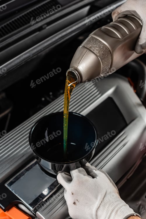 Preview: partial view of mechanic pouring machine oil at car engine