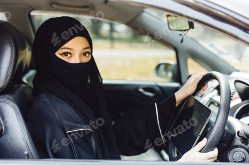 Preview: Middle Eastern Woman Driving a Car face covered black niqab dressing , Looking at Camera