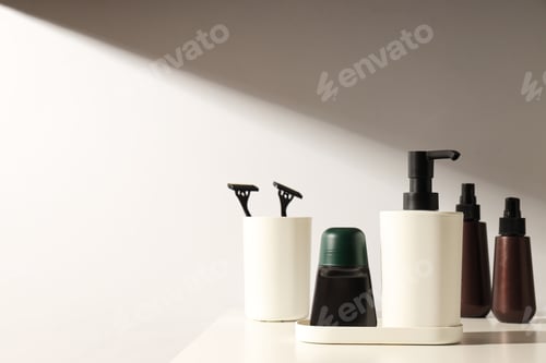 Preview: Cosmetic bottles, glass with razors and dispenser on light background, space for text
