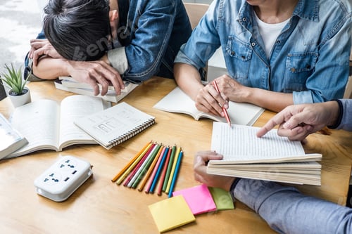 Preview: High school tutor or college student group sitting at desk in library studying and reading