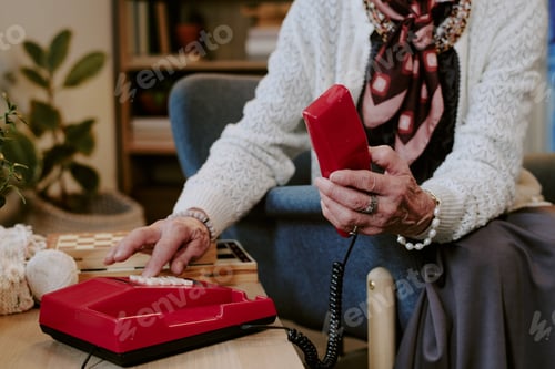 Preview: Senior Woman Dialing Landline Telephone While Sitting Indoors