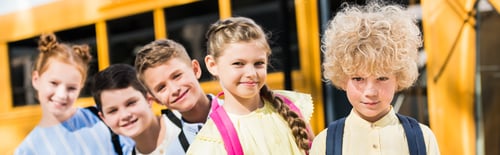 Preview: panoramic shot of group of adorable pupils looking at camera while standing in row in front of