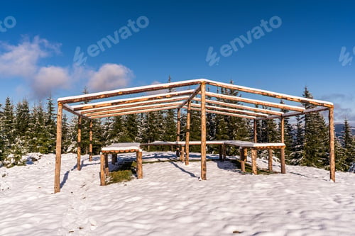 Preview: The gazebo on the top of the mountain stands in a snow-covered meadow, bathed in the light of the