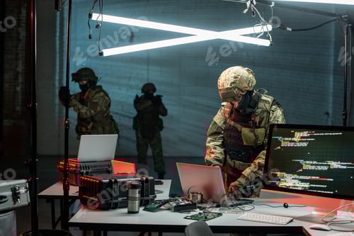 Preview: Camouflaged Team Works on Computers in a Dark Room