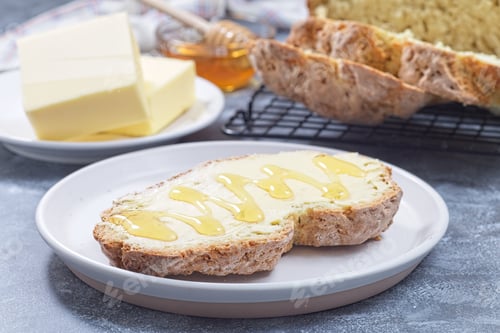 Preview: Freshly baked white Irish soda bread with butter and honey served on a plate, horizontal