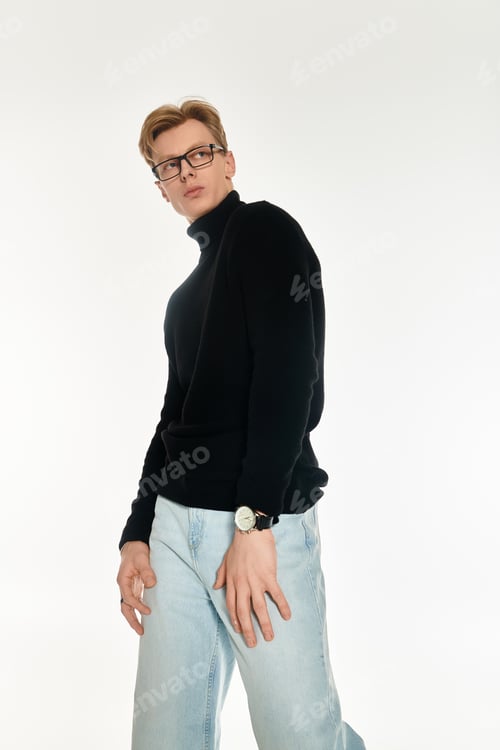 Preview: Young handsome man wearing a black sweater and jeans posing against a light background