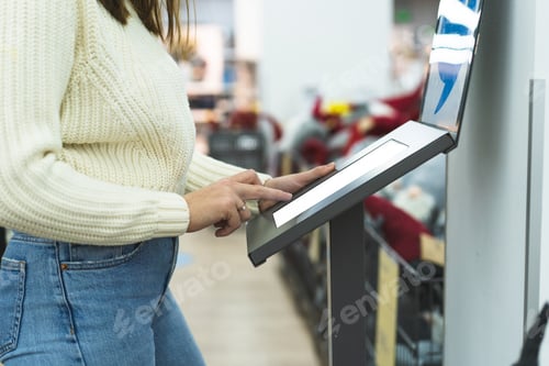 Preview: Young woman use electronic display in a store. Maintain a safe distance from others at the store