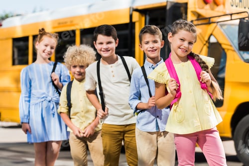 Preview: group of happy schoolchildren looking at camera in front of school bus