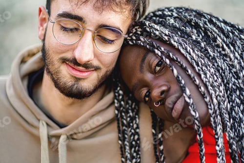 Preview: Affectionate biracial couple sitting outdoors - close up shot