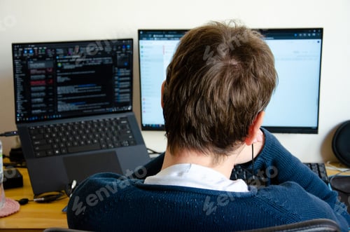 Preview: a man working on computer monitor seen from back