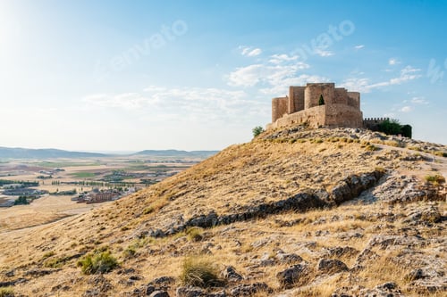 Preview: Fortified castle in a hill with fields and village on the horizon