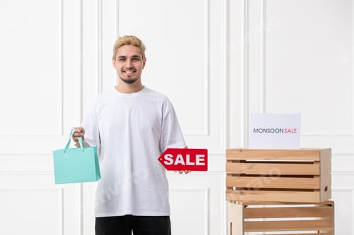 Preview: monsoon sale young salesman offering discount at clothing store with shopping bag