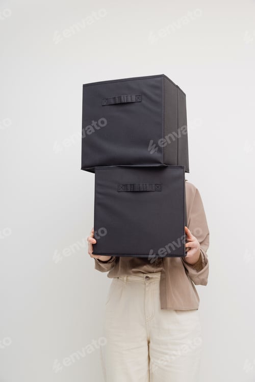 Preview: Woman holding boxes for closet organization or moving house. Faceless.