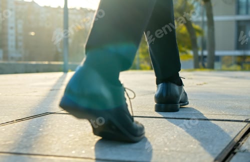 Preview: Legs of a businessman in fashionable shoes walking outdoors. Business concept.