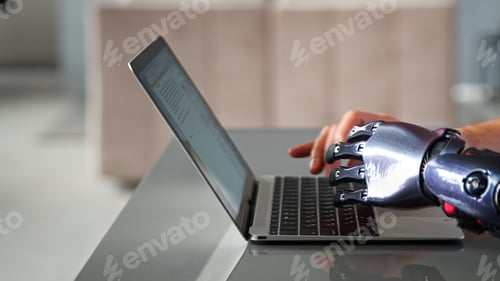Preview: Black bio limb prothesis and healthy hand appear over laptop and type on keyboard
