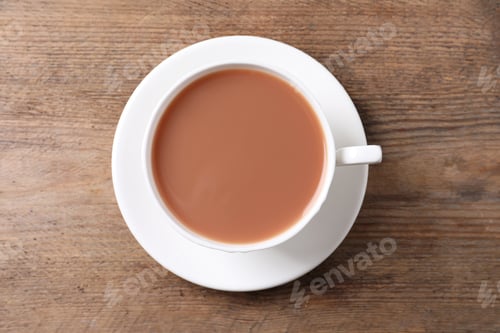 Preview: Delicious tea with milk in white cup on wooden table, top view