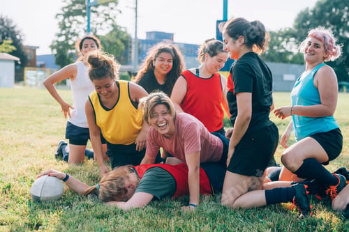 Preview: Friends laughing together during a casual game of rugby